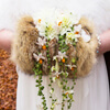 Hochzeitsmuff mit Weißen Dahlien, Erbsenpflanze, Fresienblüten und Miniorchideen auf einem Muff aus Fuchsfell.