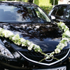 Autoschmuck aus grünen Hortensien und weißen Rosen und Schleierkrau auf der Motorhaube der Hochzeitskutsche.