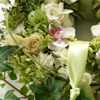 Weiße grüner Tischschmuck als Kranz aus Orchideen, Rosen, Hortensien, Schleierkraut und Efeu.
