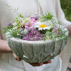 Tichdekoration, eine Schale umwickelt mit Eselsohr und reich gefüllt mit einer bunten Auswahl von Blumen.