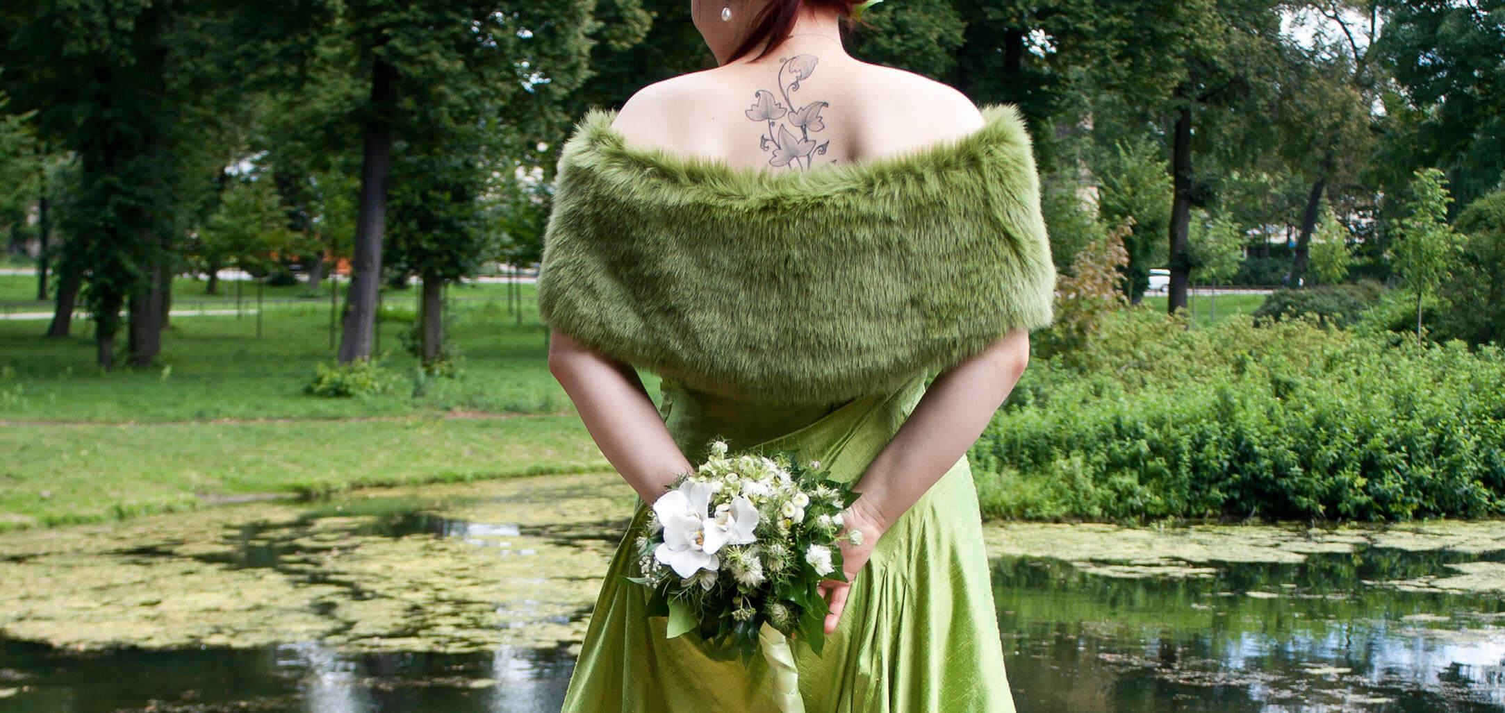 Anne Demmig trägt ihren Brautstrauss aus Orchidee, Nigella und Kamille hinter dem Rücken.